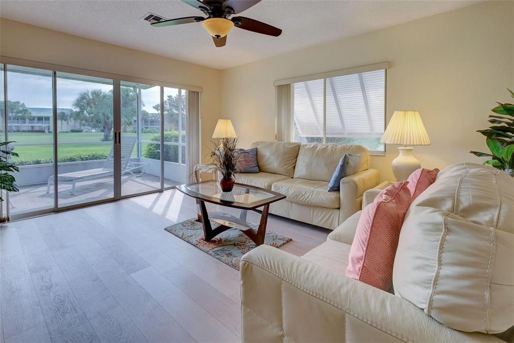 A living room features light-colored leather sofas, a glass coffee table, and sliding glass doors — 314 CERROMAR WAY N UNIT 16, VENICE, FL