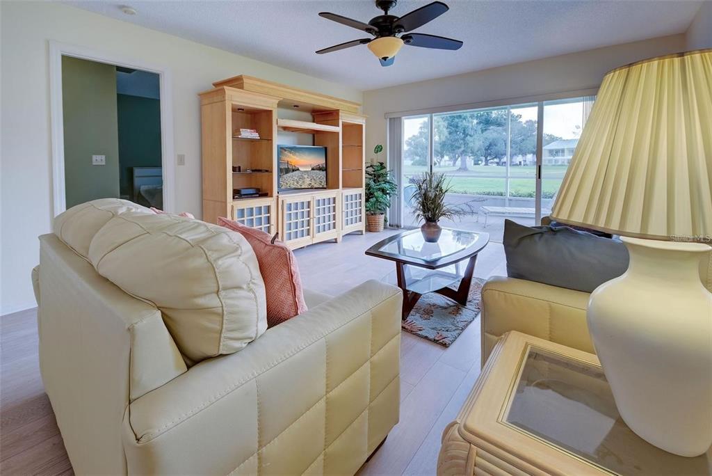 A living room features light-colored sofas, a wooden entertainment center, and sliding glass doors — 314 CERROMAR WAY N UNIT 16, VENICE, FL