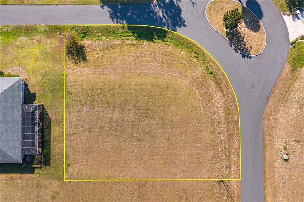 An aerial view shows a vacant, corner residential lot outlined in yellow next to a house — 1117 MYRTLE BREEZES COURT, FRUITLAND PARK, FL