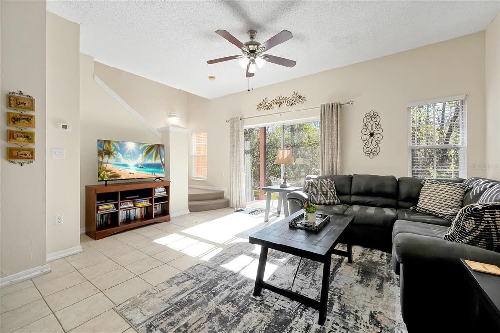 A living room features a dark sectional sofa, a television on a stand, and tile flooring — 2727 SUN KEY PLACE, KISSIMMEE, FL