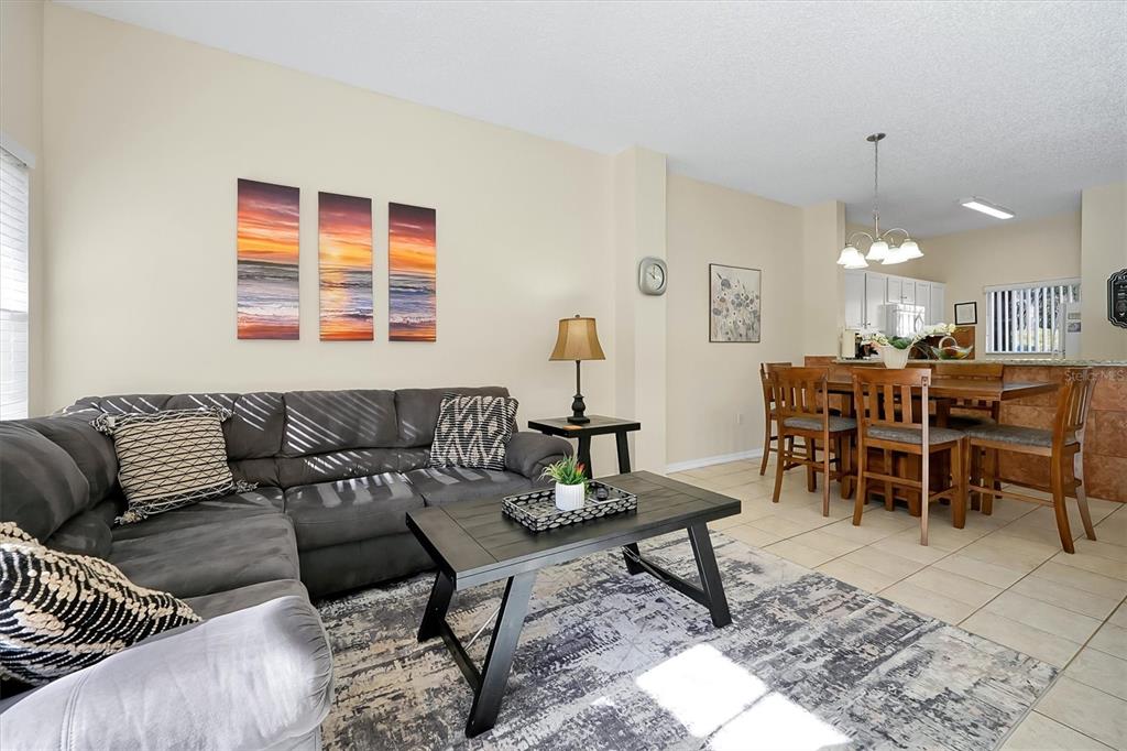 A living room with a gray sectional sofa, coffee table, and an adjacent dining area — 2727 SUN KEY PLACE, KISSIMMEE, FL