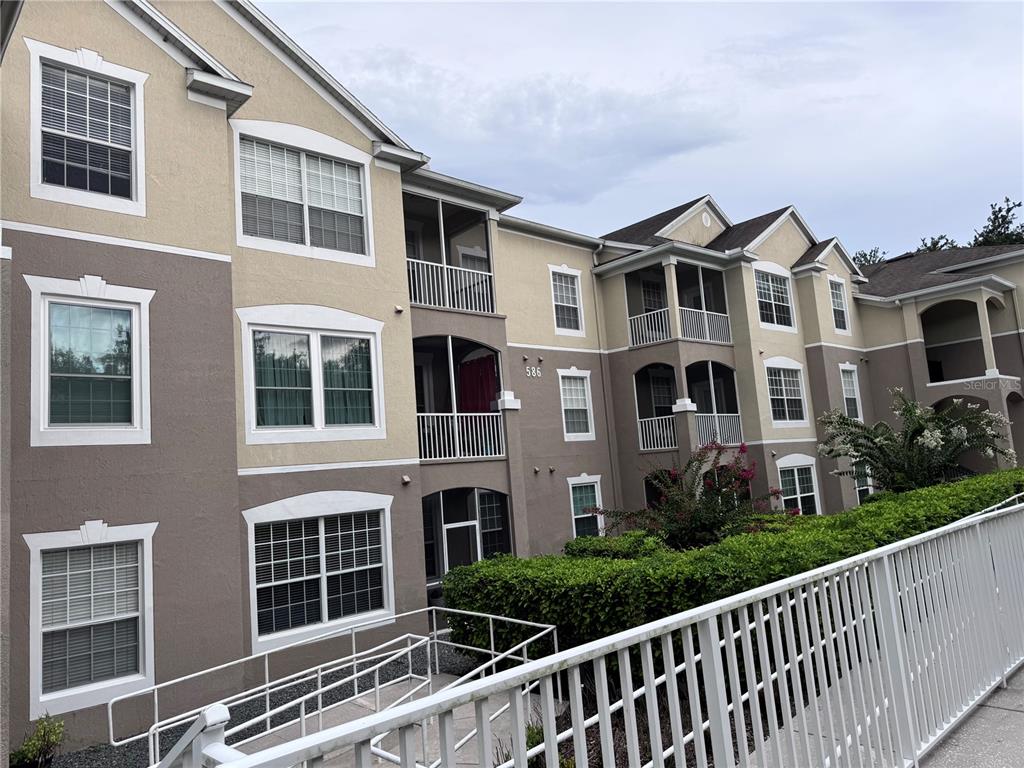 A multi-story apartment building exterior features tan and brown stucco walls with white trim — 586 BRANTLEY TERRACE WAY UNIT 301, ALTAMONTE SPRINGS, FL