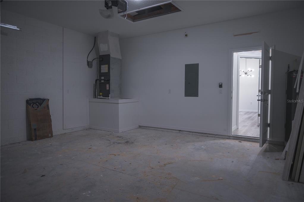 An unfinished garage features a concrete floor, an HVAC unit, and an open doorway — 10034 N DARWIN WAY, CITRUS SPRINGS, FL