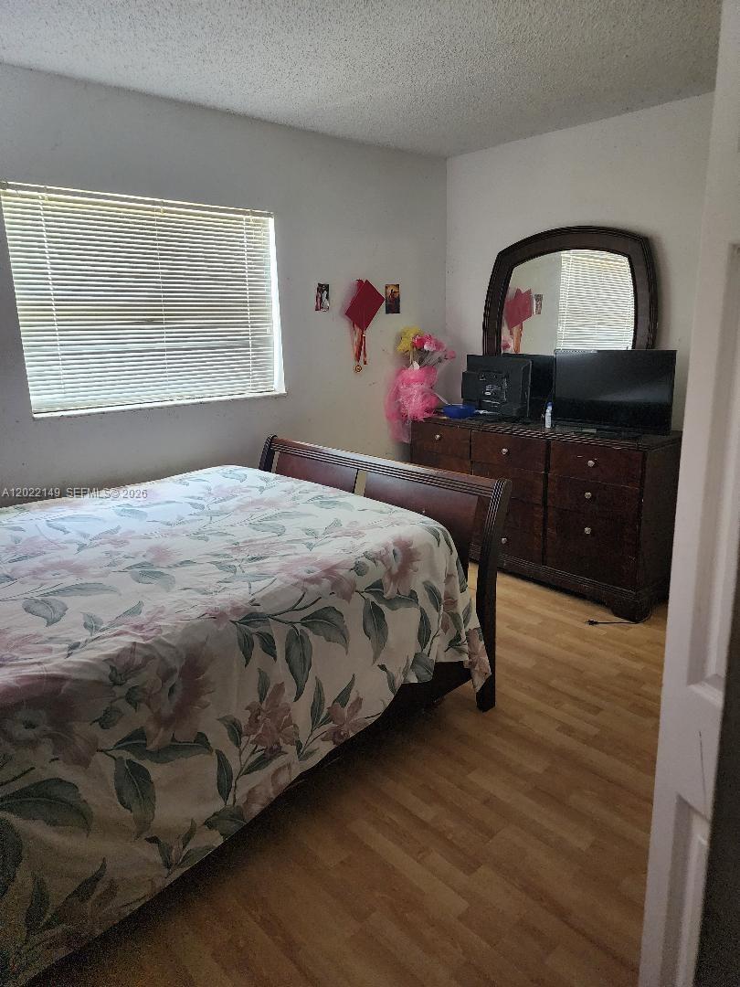 A bedroom features a bed with a floral comforter, a wooden dresser, and a mirror — 1331 S Dixie Hwy # 316, Deerfield Beach FL 33441, DEERFIELD BEACH, FL