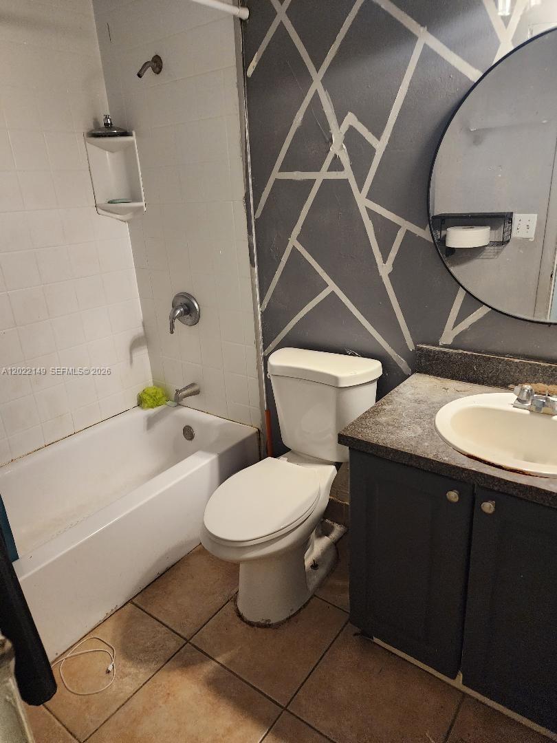 A bathroom features a white bathtub, a toilet, and a vanity with a circular mirror — 1331 S Dixie Hwy # 316, Deerfield Beach FL 33441, DEERFIELD BEACH, FL