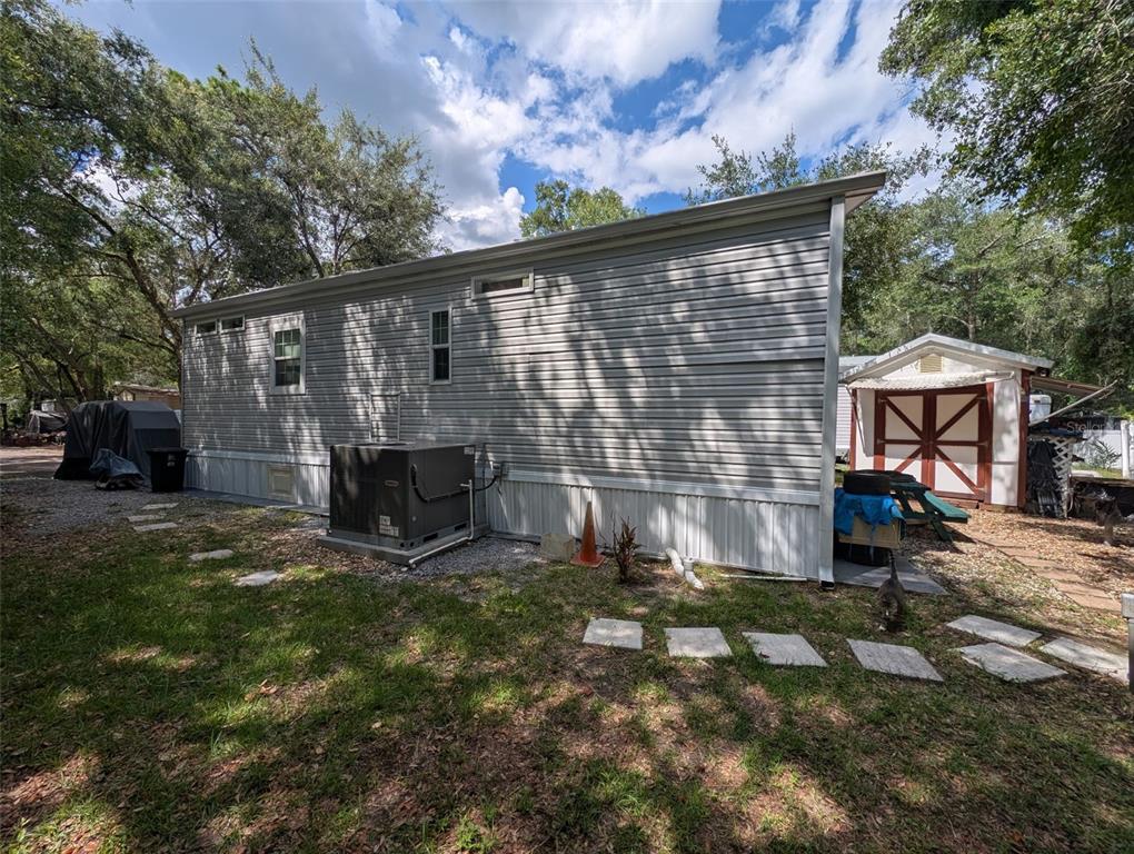The exterior side view of a manufactured home features light gray siding and an HVAC unit — 25364 NE 139TH LOOP, FORT MC COY, FL