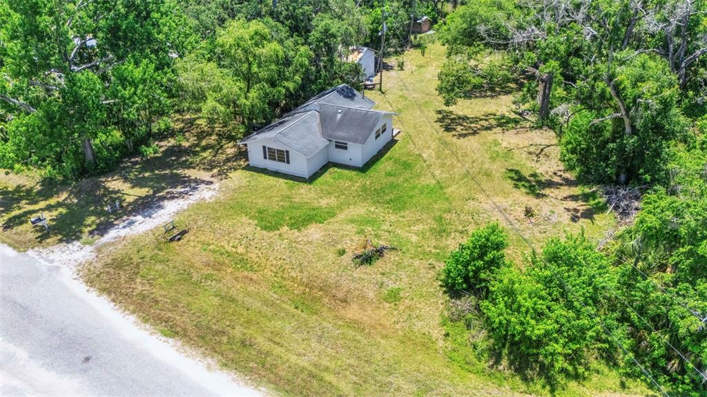 An aerial view shows a white house with a dark roof situated on a grassy lot — 8010 BROWER DRIVE, BRADENTON, FL