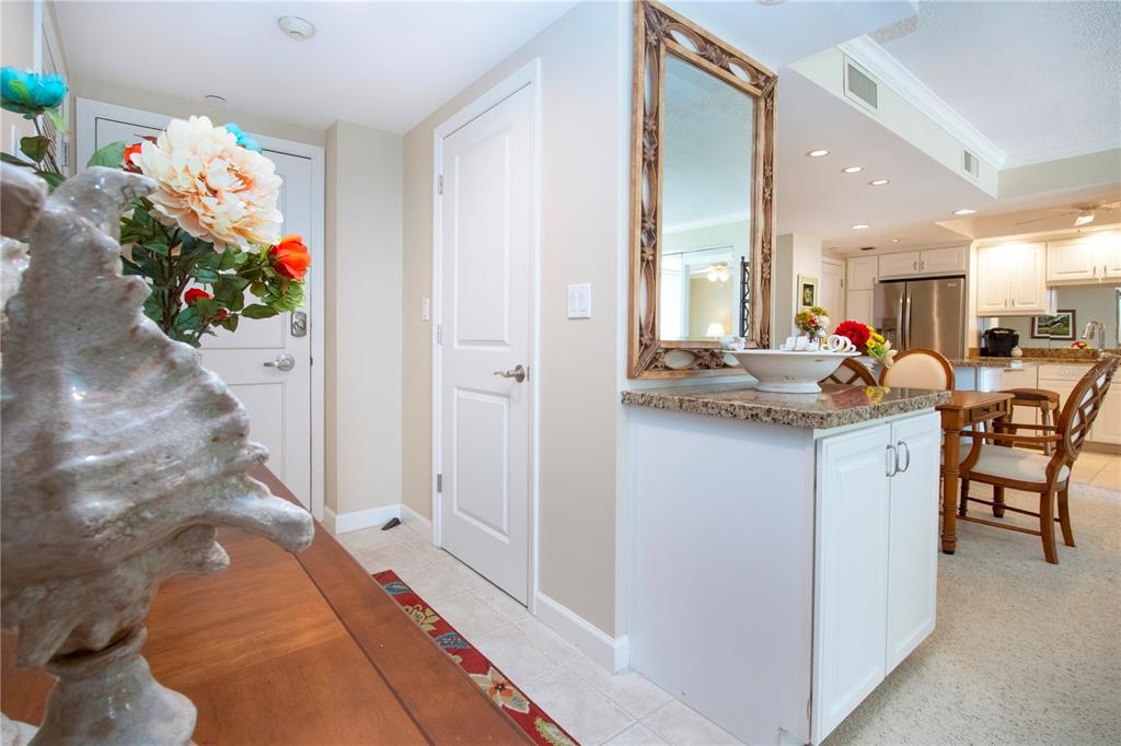 An entryway features a white cabinet with a granite top, a mirror, and a door — 1212 BENJAMIN FRANKLIN DRIVE UNIT 607, SARASOTA, FL