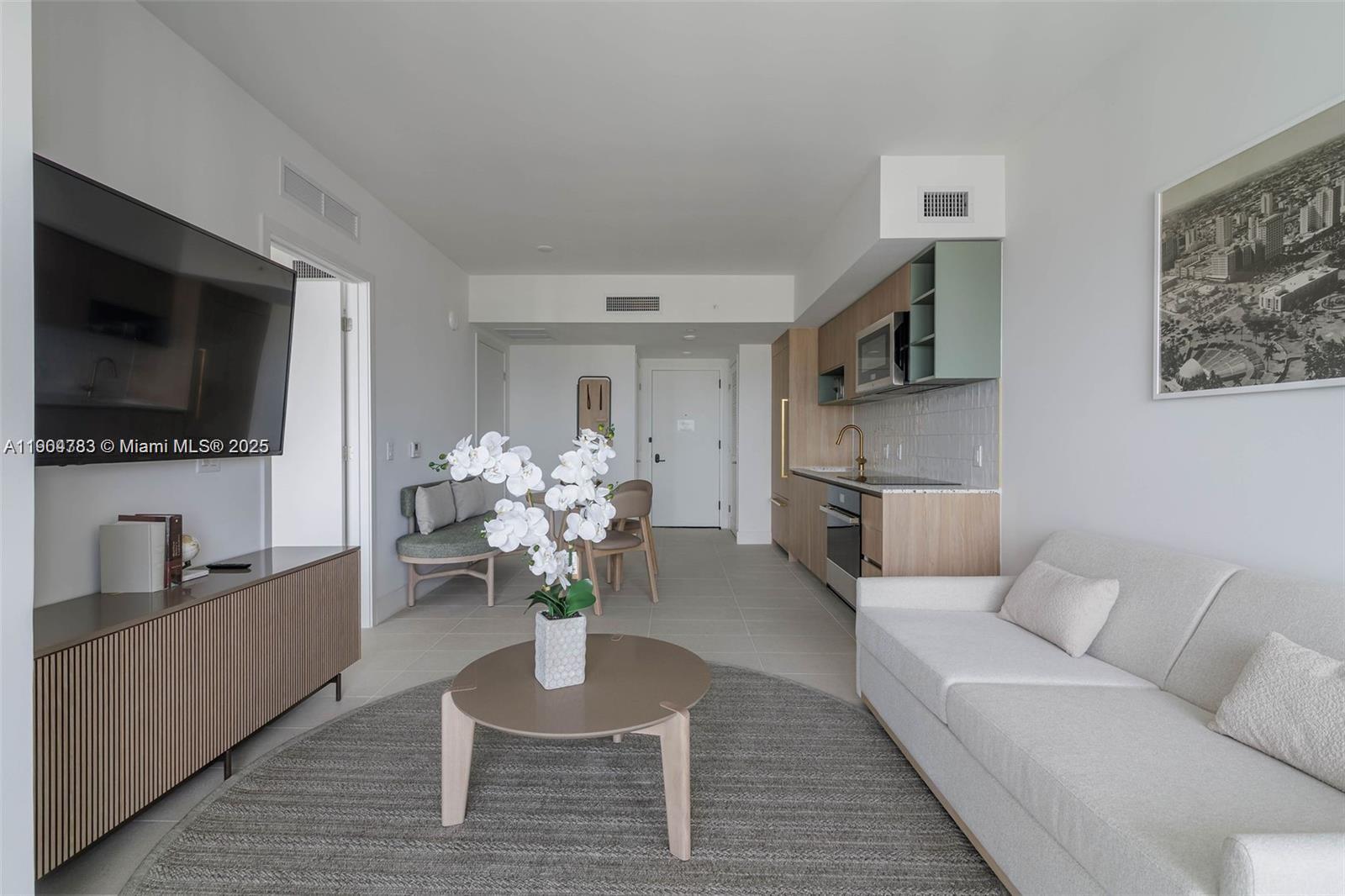 A modern studio apartment features a kitchenette, living area, and neutral contemporary furnishings — 159 NE 6th St # 3404, Miami FL 33132, MIAMI, FL
