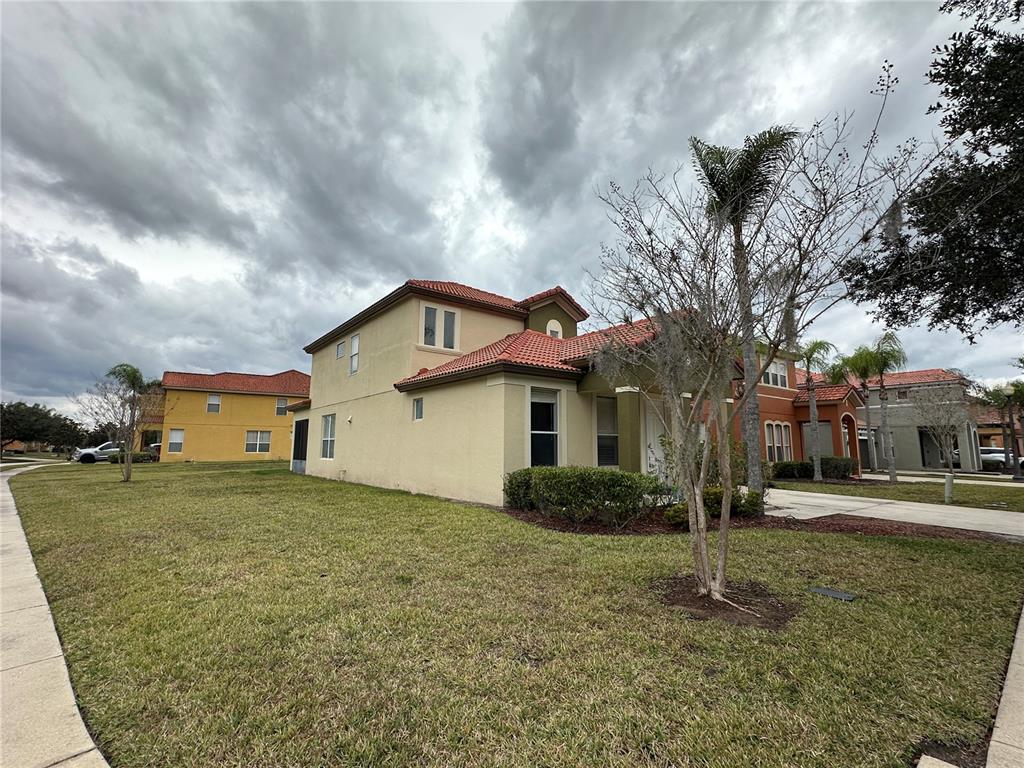 A two-story stucco house with a red tile roof sits on a grassy corner lot — 890 MARCELLO BOULEVARD, KISSIMMEE, FL