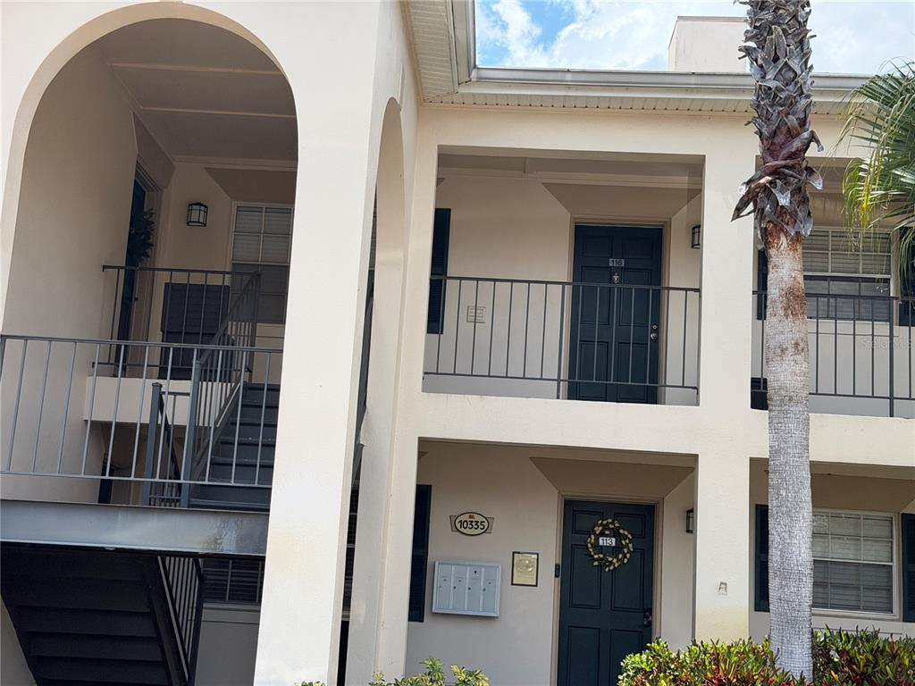 An exterior view of a two-story apartment building with stairs and a palm tree — 10335 CARROLLWOOD LANE UNIT 116, TAMPA, FL