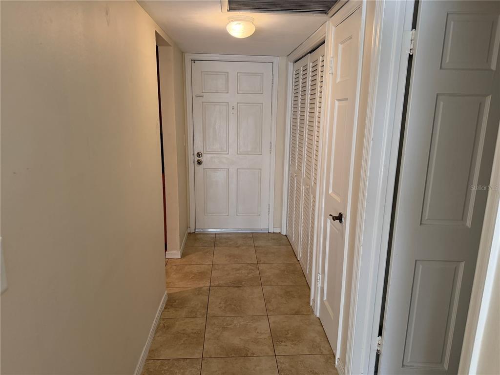 An entryway features beige tile flooring, a white front door, and white louvered closet doors — 10335 CARROLLWOOD LANE UNIT 116, TAMPA, FL