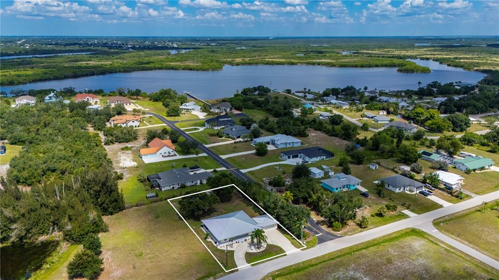 An aerial view shows a single-story house with a white outline on a grassy lot — 569 RIO VISTA AVENUE, PUNTA GORDA, FL