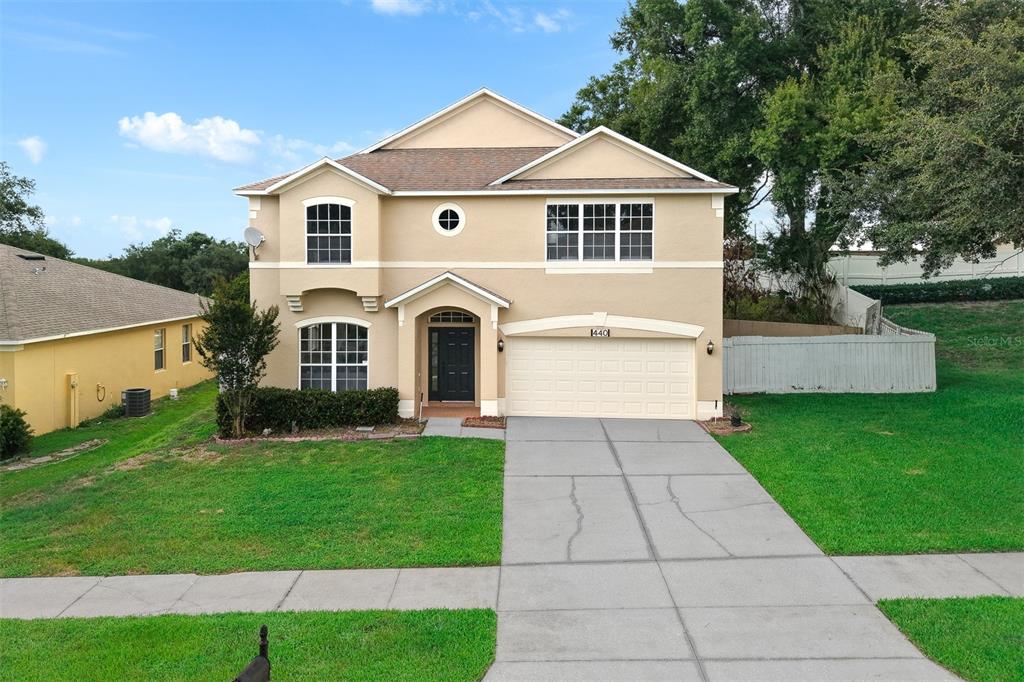 A two-story tan stucco house with a two-car garage and a concrete driveway — 440 ROB ROY DRIVE, CLERMONT, FL