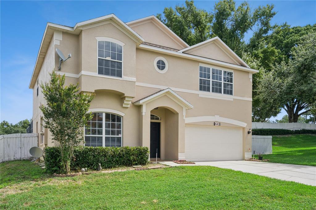 A two-story beige house with a two-car garage and a front porch — 440 ROB ROY DRIVE, CLERMONT, FL