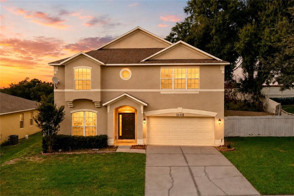 A two-story suburban house with a tan stucco exterior and an attached two-car garage — 440 ROB ROY DRIVE, CLERMONT, FL