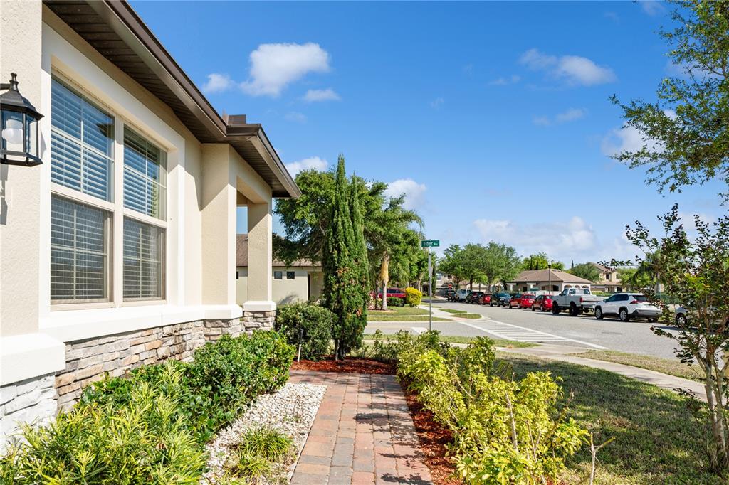 A view of a house exterior with a stone-accented wall, walkway, and street — 1110 UMBRIA LANE, ST CLOUD, FL
