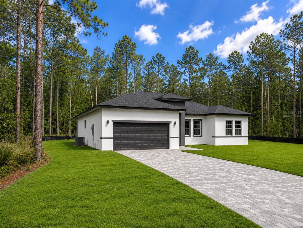 A modern, white single-story house with a dark roof and a paved driveway — 16158 SW 19TH AVENUE ROAD, OCALA, FL