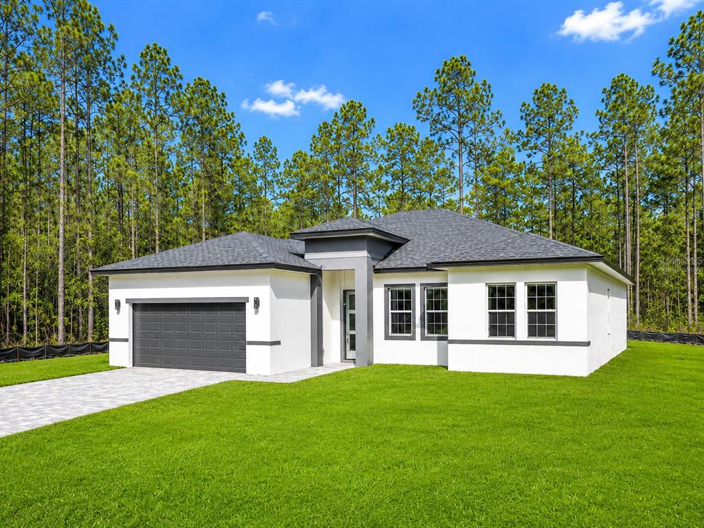 A single-story white house with a gray roof, a two-car garage, and a green lawn — 16158 SW 19TH AVENUE ROAD, OCALA, FL