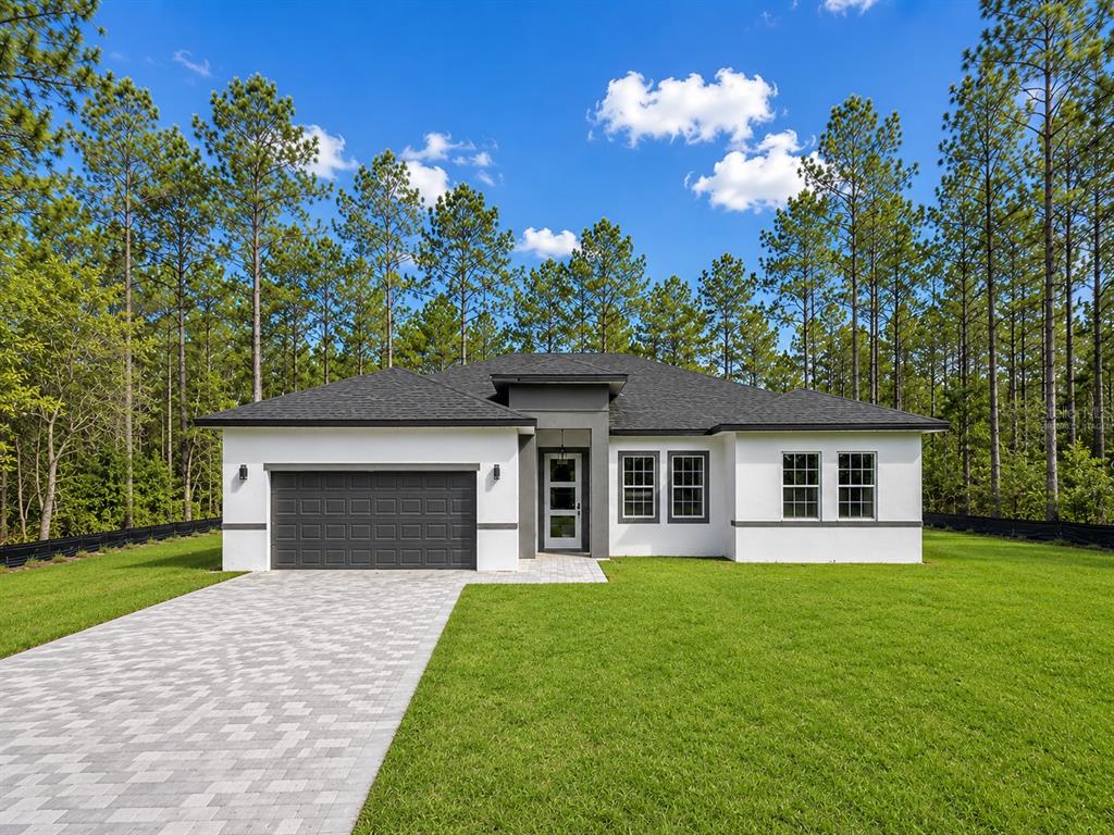 A single-story house with a white stucco exterior, dark garage door, and a paved driveway — 16158 SW 19TH AVENUE ROAD, OCALA, FL