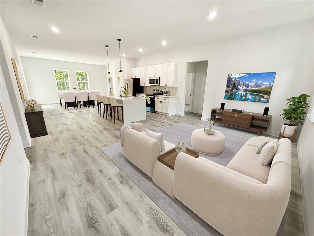 This open-concept living room and kitchen features light wood-look flooring and white cabinetry — 16158 SW 19TH AVENUE ROAD, OCALA, FL