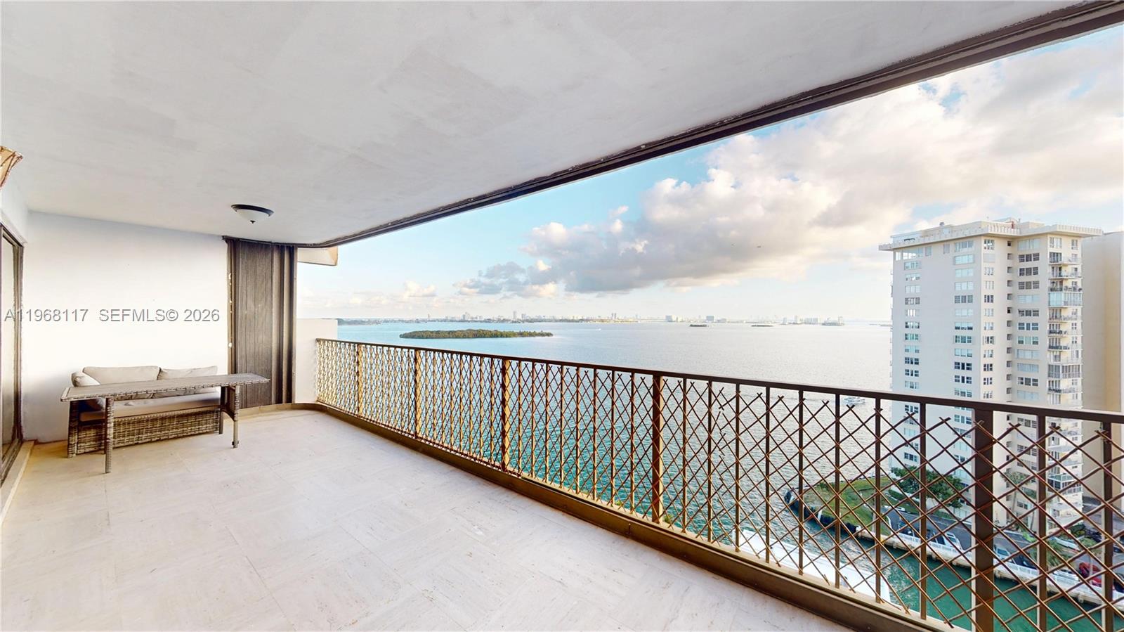 A spacious balcony features a metal lattice railing, light tile flooring, and a water view — 1800 NE 114th St # 1705, Miami FL 33181, MIAMI, FL