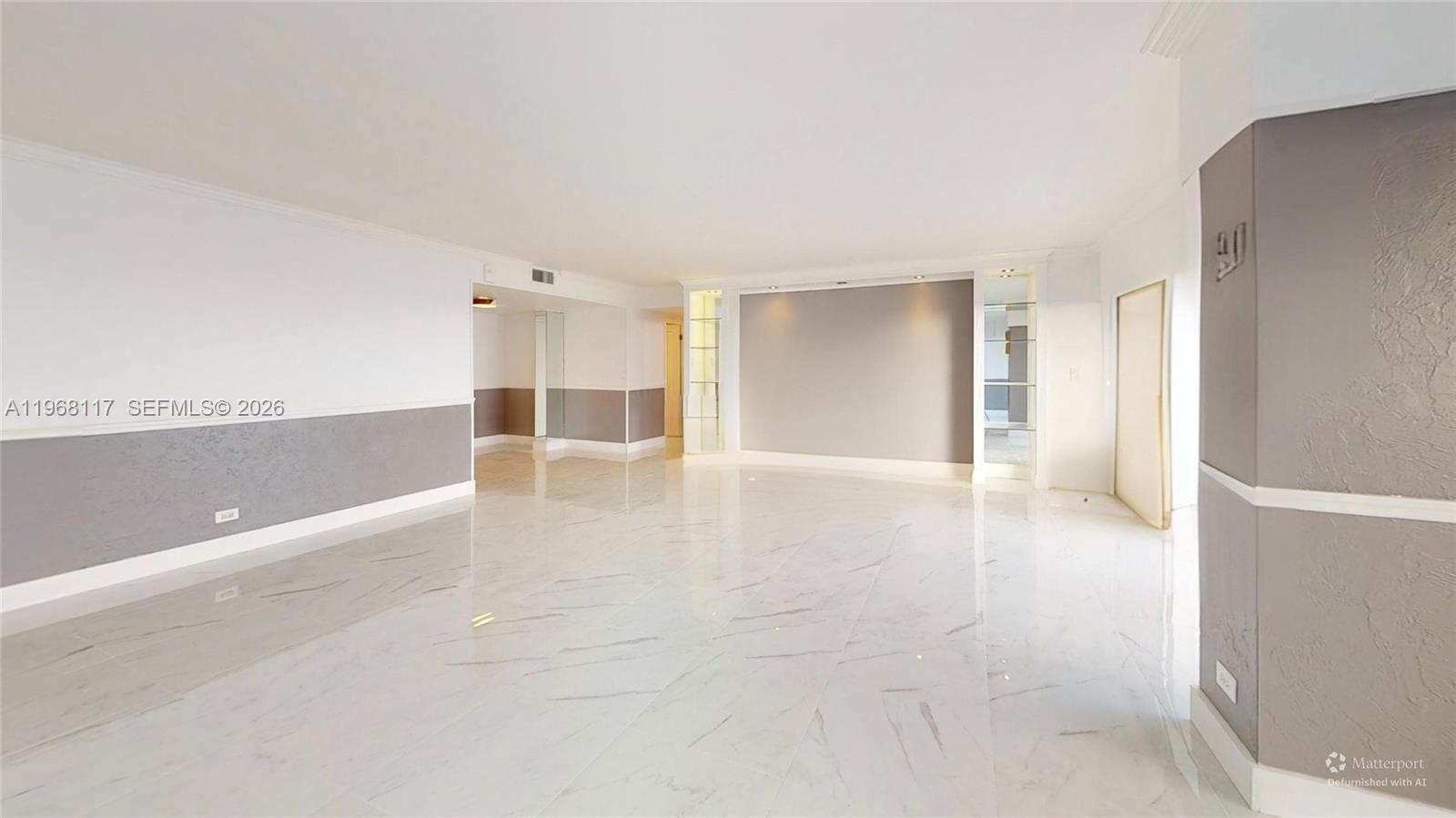 A spacious, empty room features white marble floors, gray accent walls, and recessed lighting — 1800 NE 114th St # 1705, Miami FL 33181, MIAMI, FL