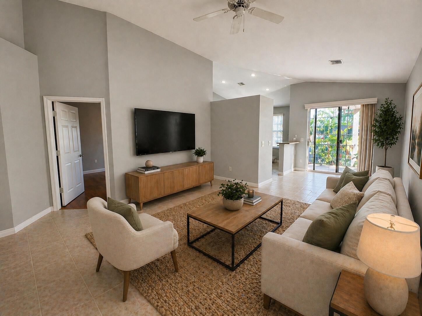 A living room features a wall-mounted television, wooden media console, sofa, armchair, and sliding doors — 7801 S Aragon Boulevard # 4, Sunrise FL 33322, SUNRISE, FL