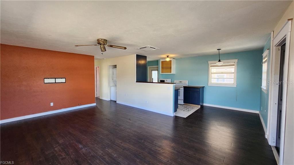 An open-concept living room and kitchen featuring dark wood flooring and contrasting wall colors — 1169 CHEROKEE AVENUE, LEHIGH ACRES, FL