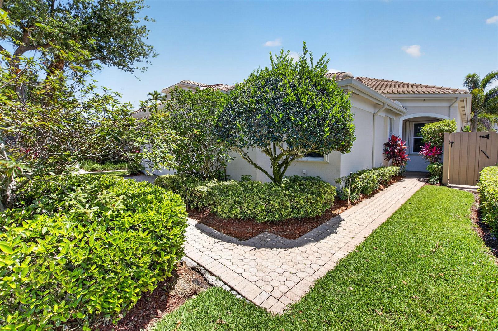 A paved walkway leads to the entrance of a house surrounded by trees and landscaping — 2408 NW 67th Street, Boca Raton FL 33496, BOCA RATON, FL