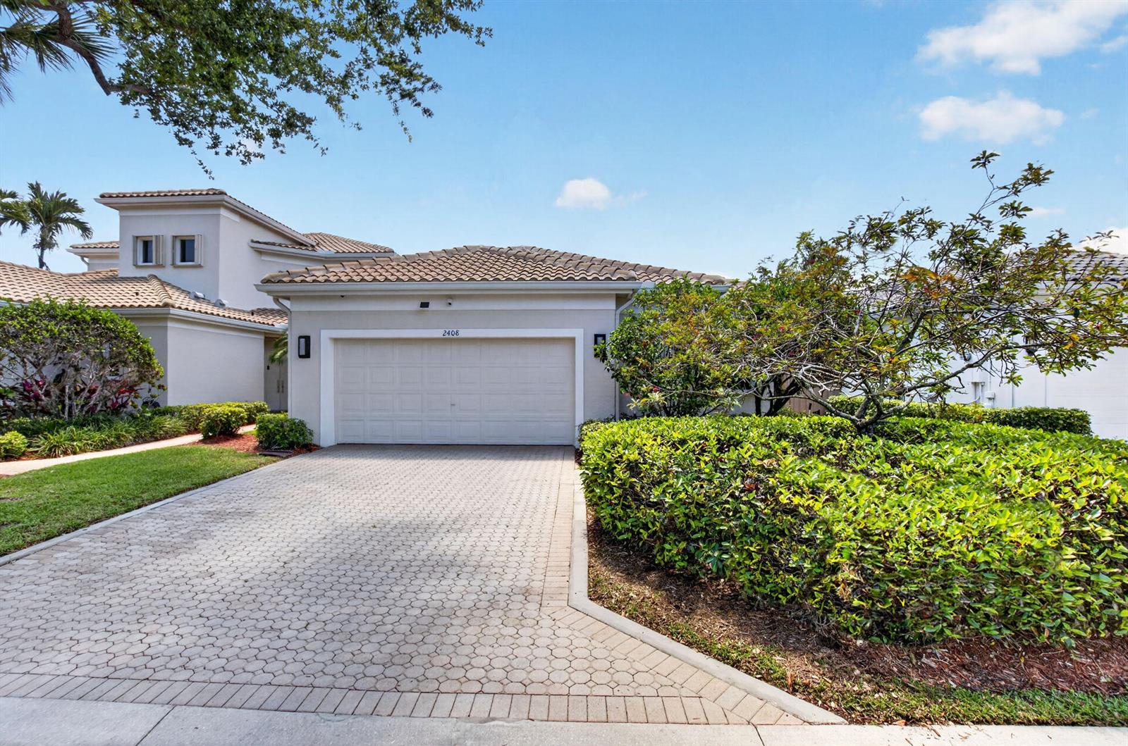 A paved driveway leads to a single-story house with a two-car garage and landscaping — 2408 NW 67th Street, Boca Raton FL 33496, BOCA RATON, FL