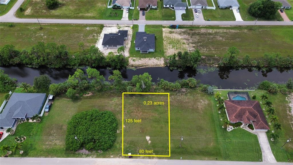 An aerial view shows a vacant rectangular lot outlined in yellow near a canal — 4140 NE 21ST PLACE, CAPE CORAL, FL
