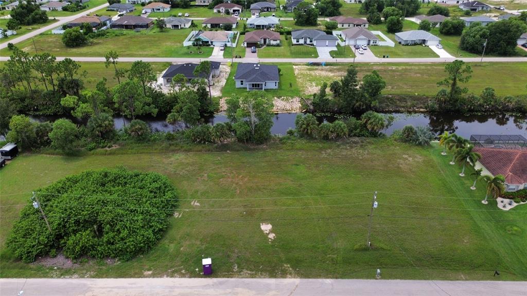 An aerial view shows a vacant residential lot bordered by a canal and neighboring houses — 4140 NE 21ST PLACE, CAPE CORAL, FL