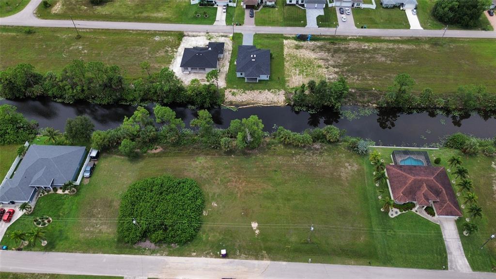 An aerial view shows a vacant residential lot situated between two houses along a canal — 4140 NE 21ST PLACE, CAPE CORAL, FL