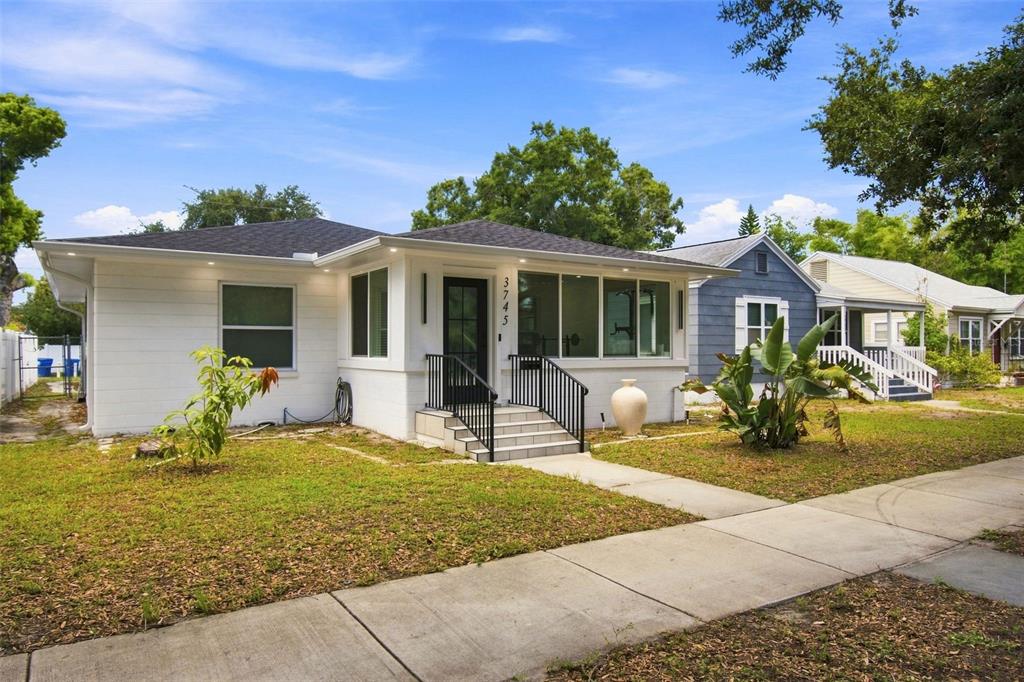 A white, single-story house with a black front door and a small concrete porch — 3745 1ST AVENUE N, ST PETERSBURG, FL