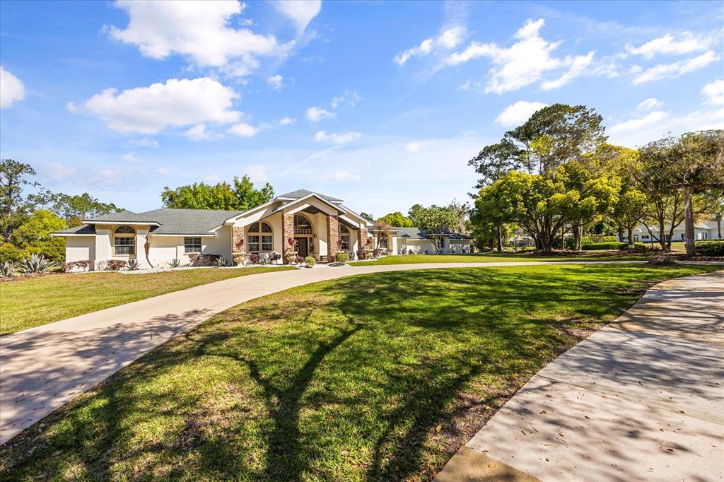 A single-story house with a stone-accented entryway and a long concrete driveway on a lawn — 1856 ALAQUA DRIVE, LONGWOOD, FL