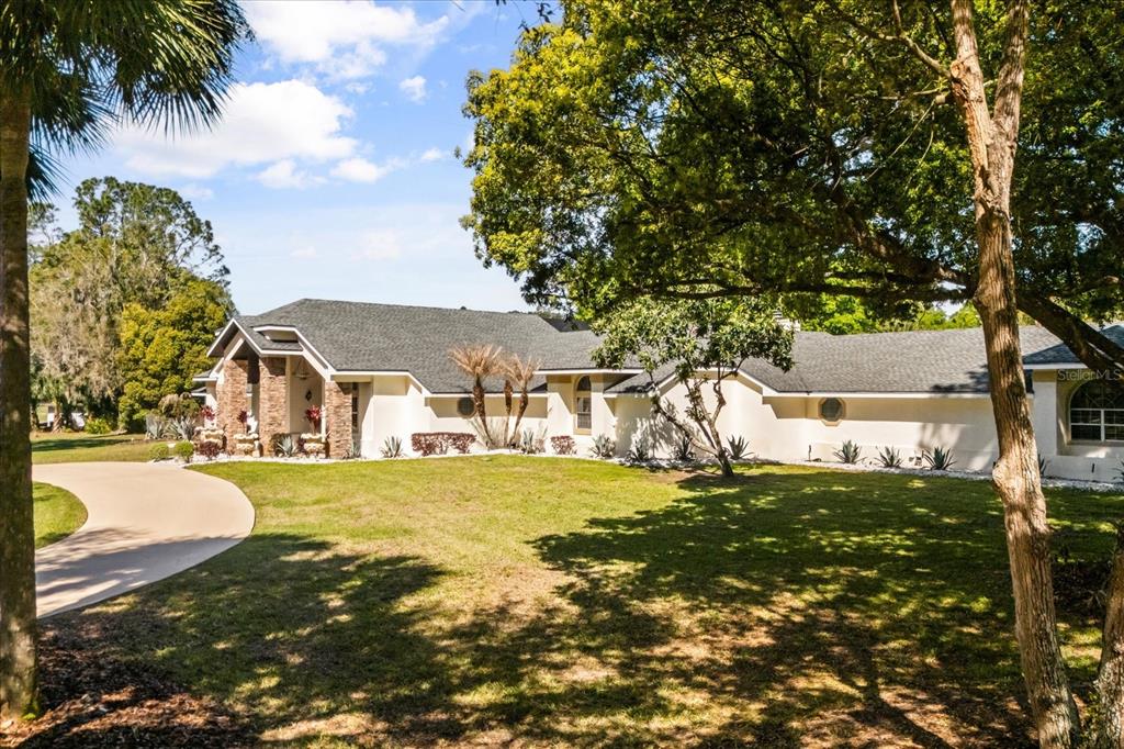 A single-story house with a stone-accented entrance and a curved driveway sits on a lawn — 1856 ALAQUA DRIVE, LONGWOOD, FL