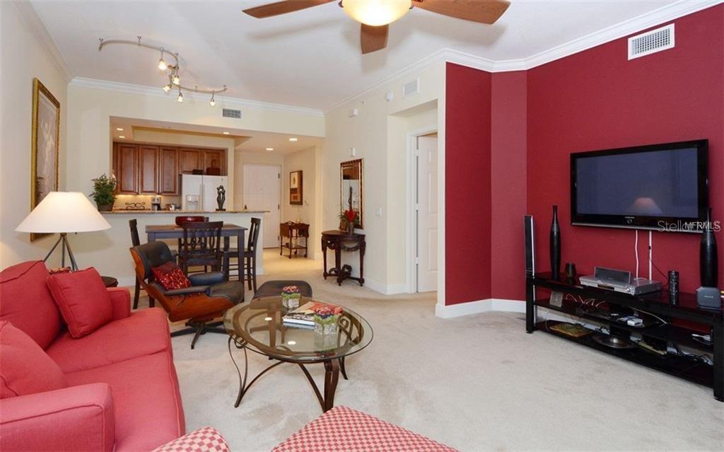 A living room features a red accent wall, a television, and an open kitchen area — 100 CENTRAL AVENUE UNIT 620, SARASOTA, FL
