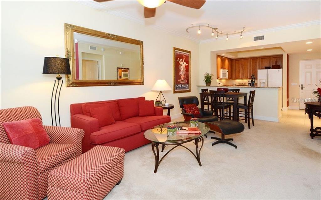 A living room with a red sofa and armchair, a glass coffee table, and kitchen — 100 CENTRAL AVENUE UNIT 620, SARASOTA, FL