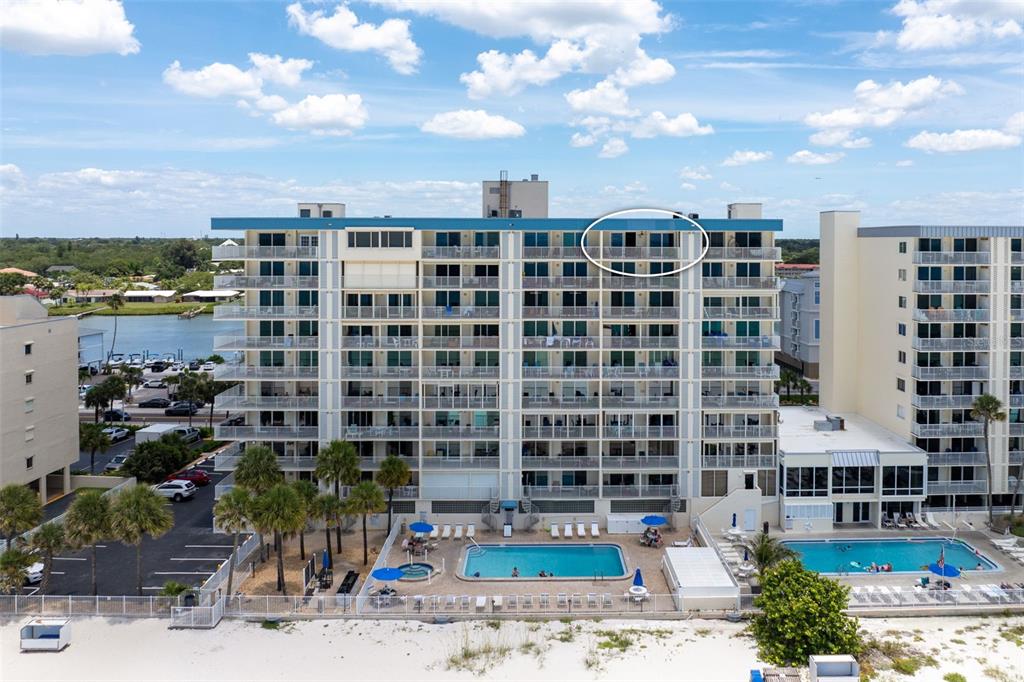 An aerial view of a multi-story beachfront condominium building with a pool and parking lot — 20002 GULF BOULEVARD UNIT 2, INDIAN SHORES, FL