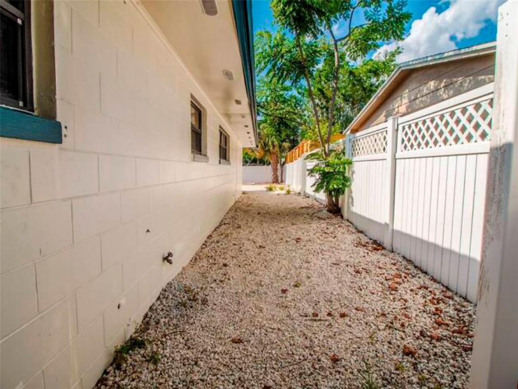 A narrow side yard features a white block wall, gravel ground, and a white fence — 4401 LENMORE STREET UNIT 2, ORLANDO, FL