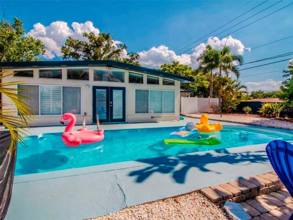 A backyard swimming pool with inflatable floats sits in front of a single-story house — 4401 LENMORE STREET UNIT 2, ORLANDO, FL