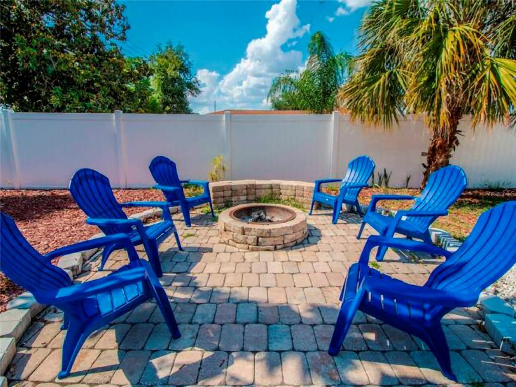 A stone fire pit sits on a paved patio surrounded by six blue Adirondack chairs — 4401 LENMORE STREET UNIT 2, ORLANDO, FL