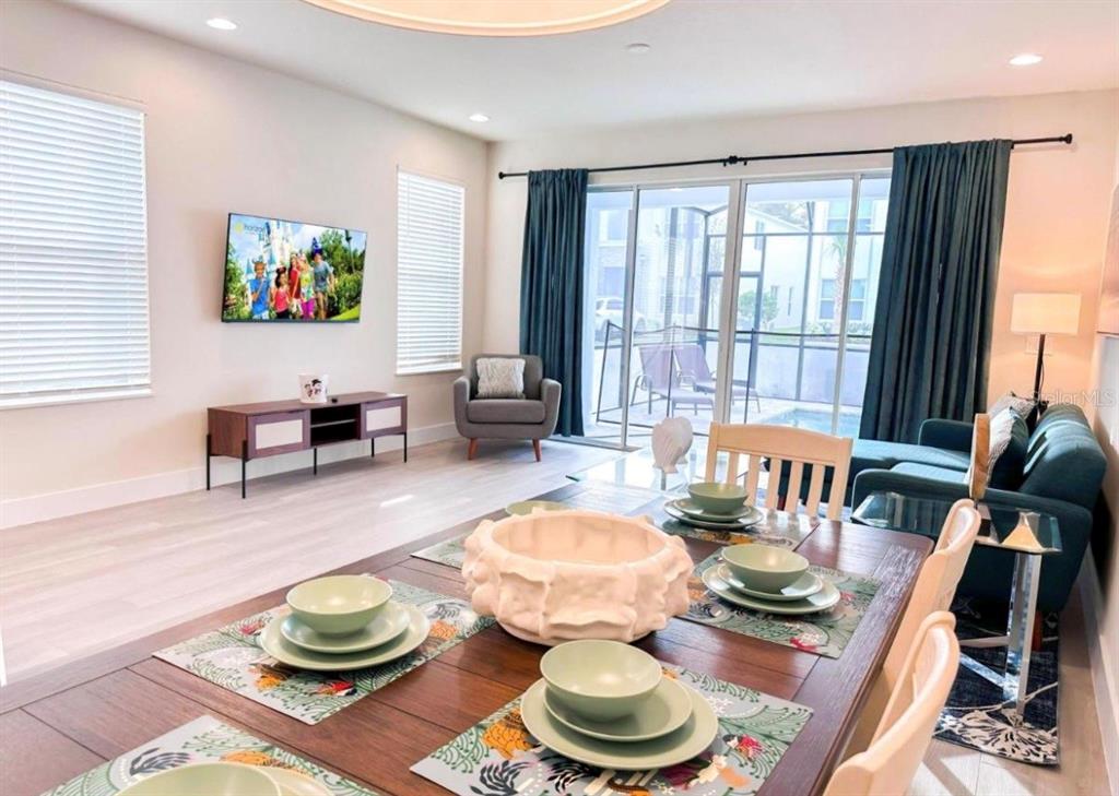 A dining area with a table and chairs opens into a living room with patio access — 1399 PEACEFUL NATURE WAY, CLERMONT, FL
