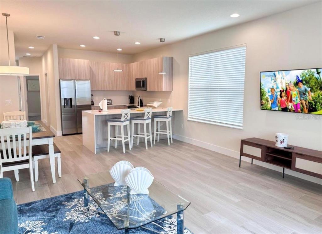 An open-concept kitchen and living area features light wood cabinetry, a breakfast bar, and flooring — 1399 PEACEFUL NATURE WAY, CLERMONT, FL
