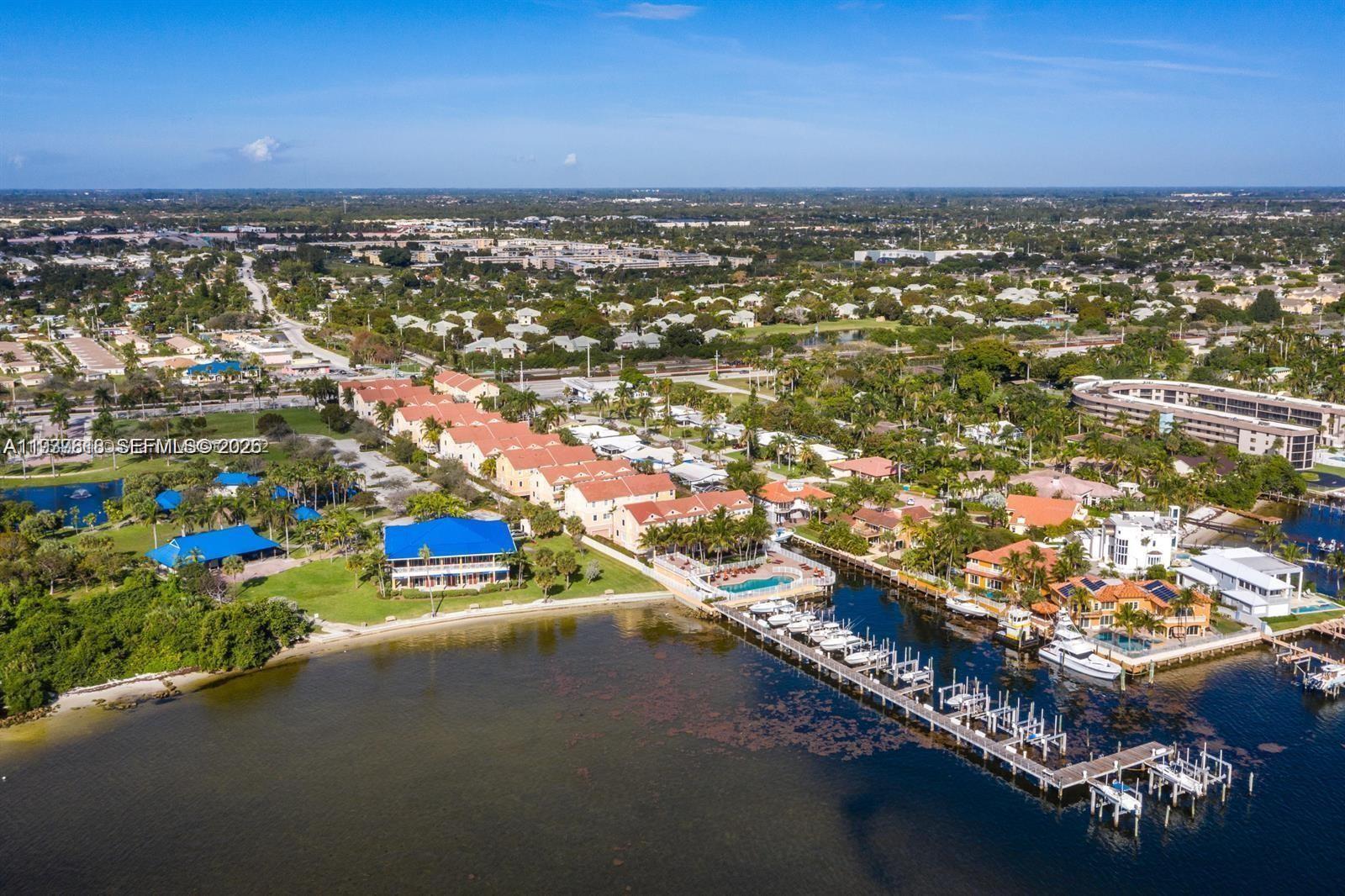 An aerial view shows a waterfront residential complex with a long dock and swimming pool — 104 Harbors Way, Boynton Beach FL 33435, BOYNTON BEACH, FL