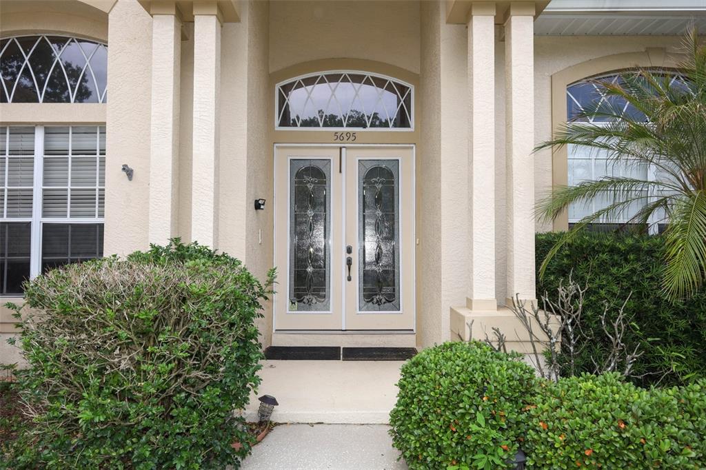 The exterior of a house features a double front door with glass inserts and columns — 5695 POND PINE POINT, OVIEDO, FL