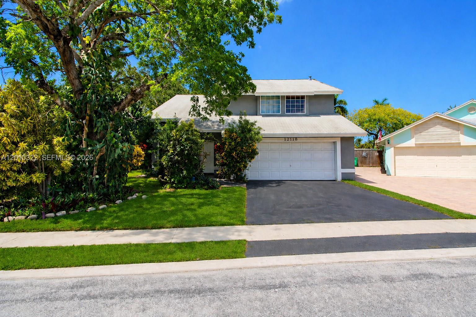 A two-story house with a white garage, gray siding, and a paved driveway — 12113 NW 33rd St, Sunrise FL 33323, SUNRISE, FL