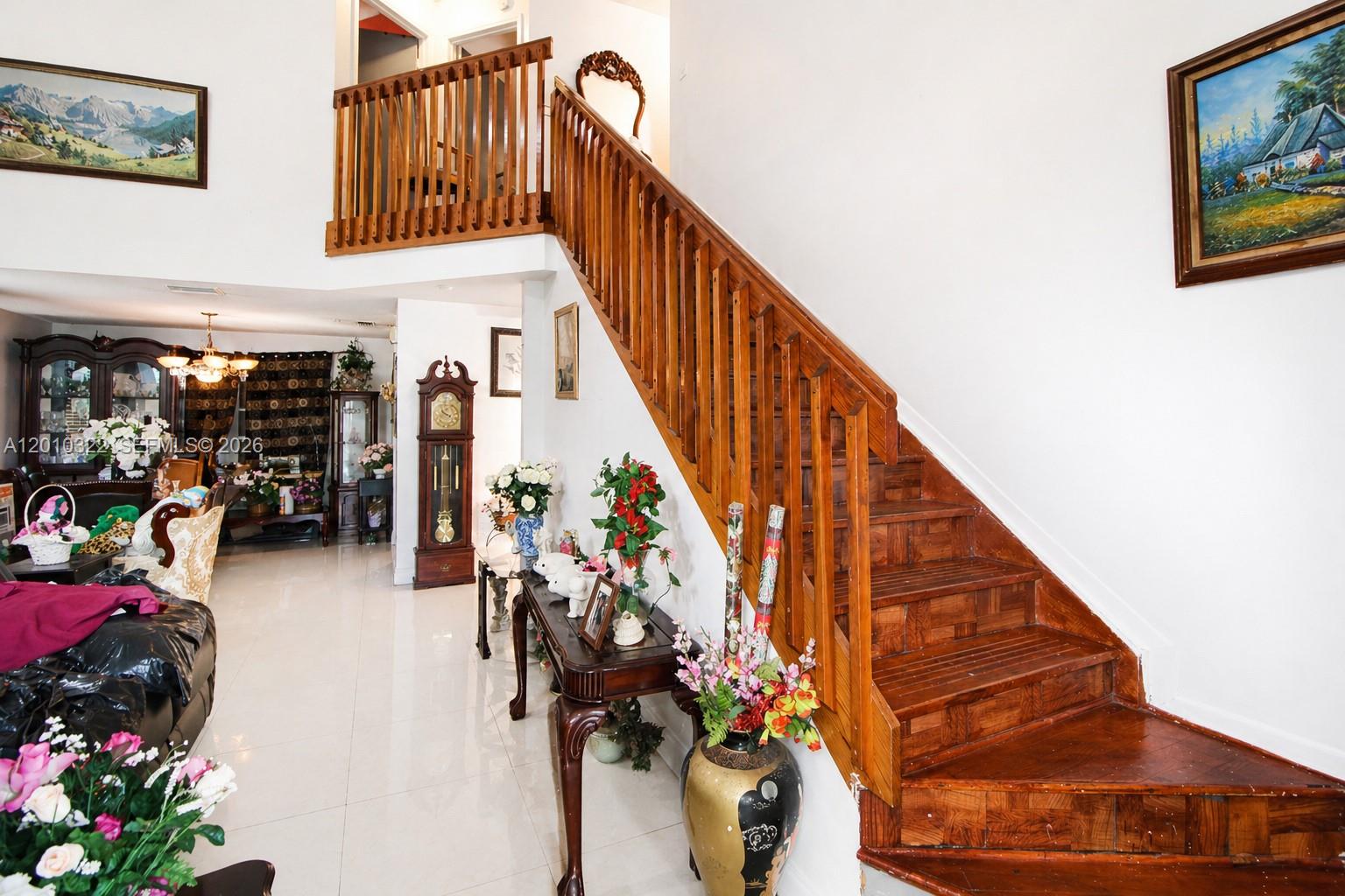 A wooden staircase with a railing leads to a landing in a tiled entryway — 12113 NW 33rd St, Sunrise FL 33323, SUNRISE, FL