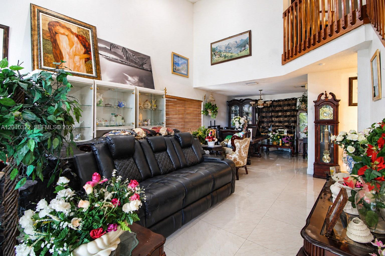 A high-ceilinged living room features a black leather sofa, tile flooring, and a grandfather clock — 12113 NW 33rd St, Sunrise FL 33323, SUNRISE, FL